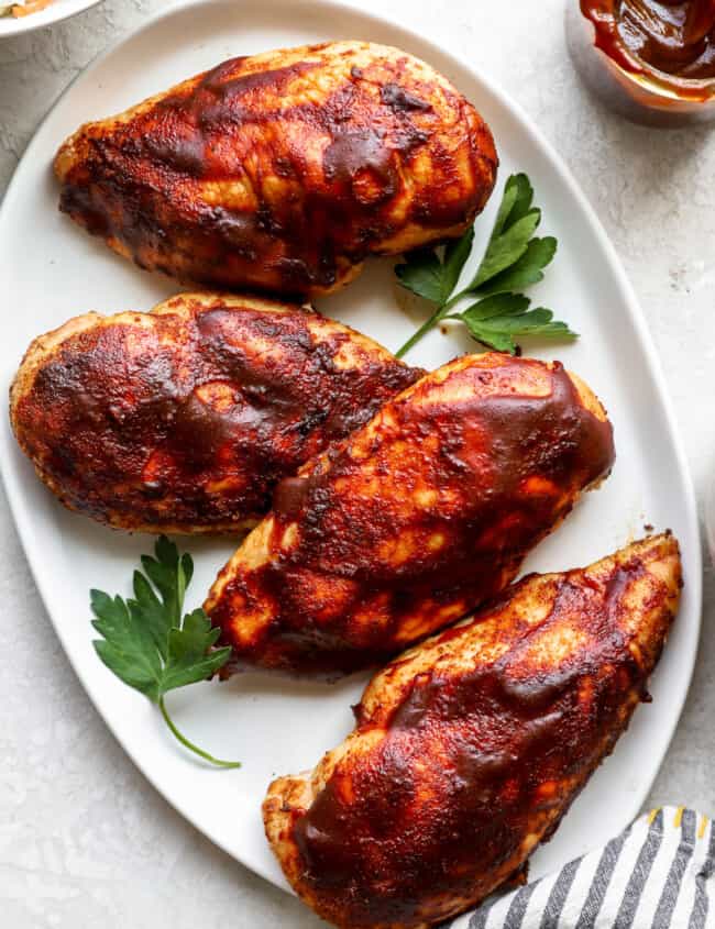 bbq chicken breasts on a white plate.