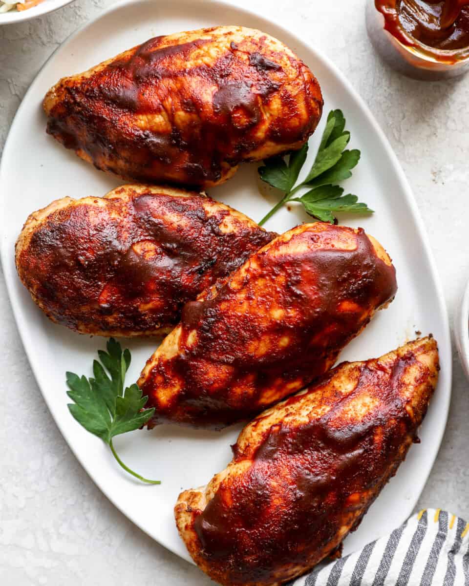 bbq chicken breasts on a white plate.