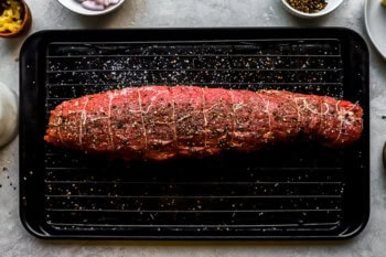 seasoned tied beef tenderloin on a wire rack set in a baking sheet.