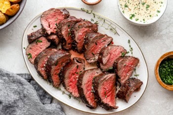 sliced beef tenderloin on a white oval plate.