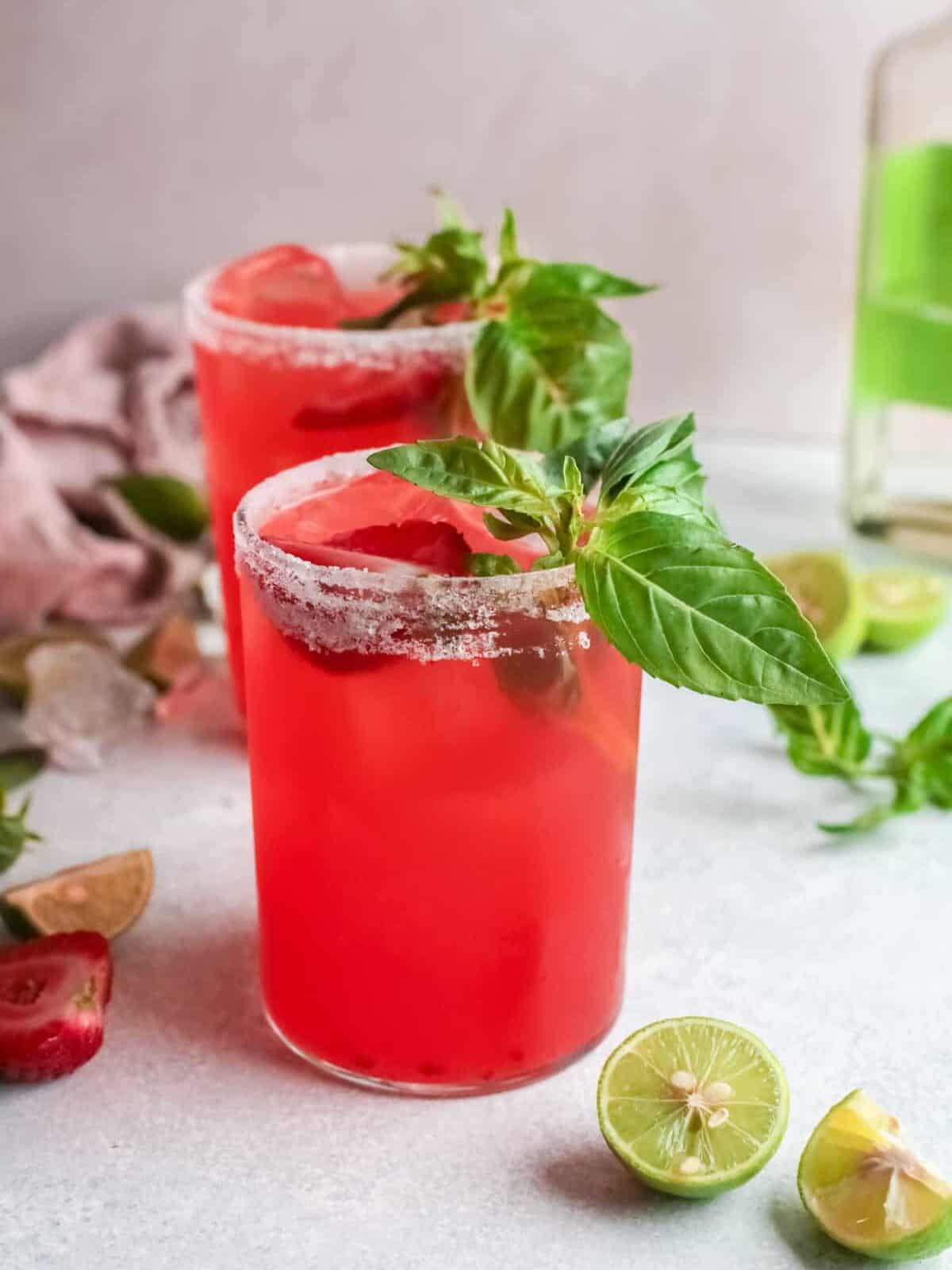 three-quarters view of 2 strawberry basil margaritas, one in front of the other.