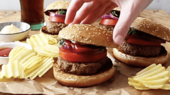 A turkey burger topped with tomato, onion, and greens on a bun.