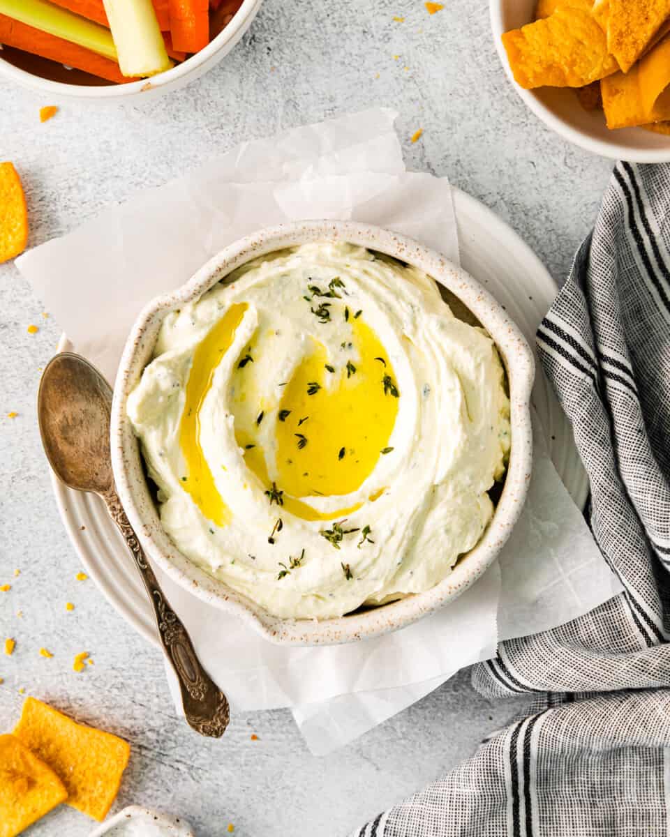 overhead view of whipped feta dip in a white bowl with olive oil on top.