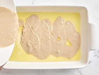 pouring batter over melted butter in a baking dish.