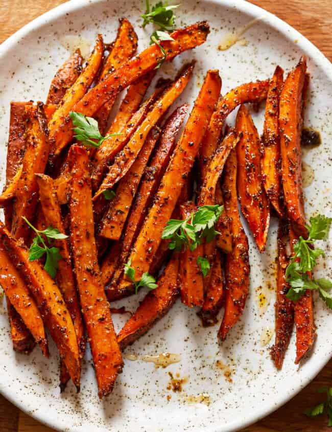 sweet potato fries on a plate with herbs.