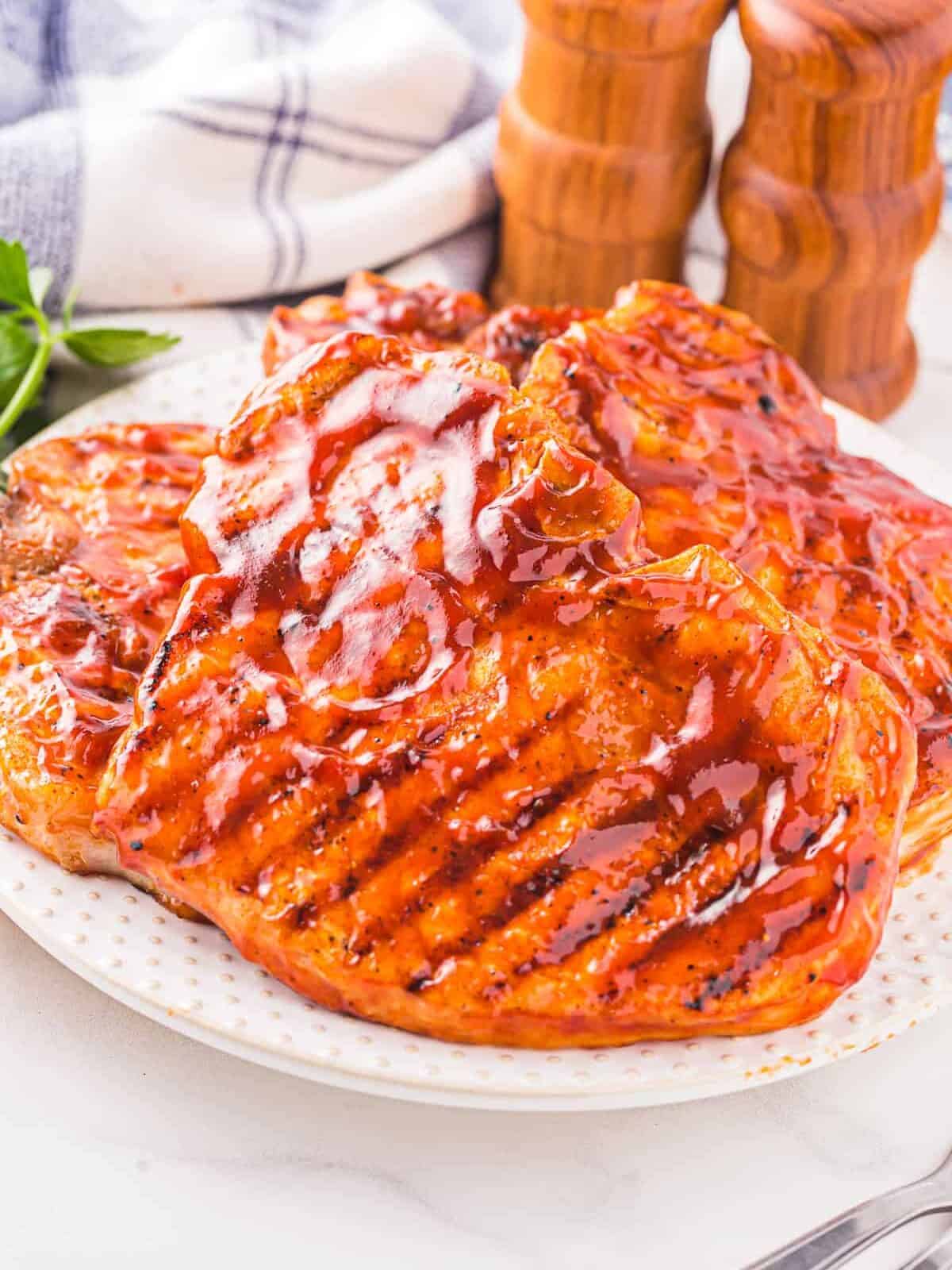 three-quarters view of bbq pork chops on a white plate.