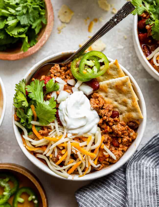 a bowl of chili with sour cream and tortilla chips.