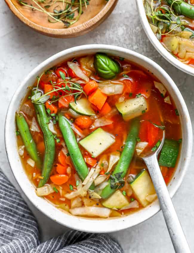 overhead view of a serving of cabbage soup in a white bowl with a spoon.