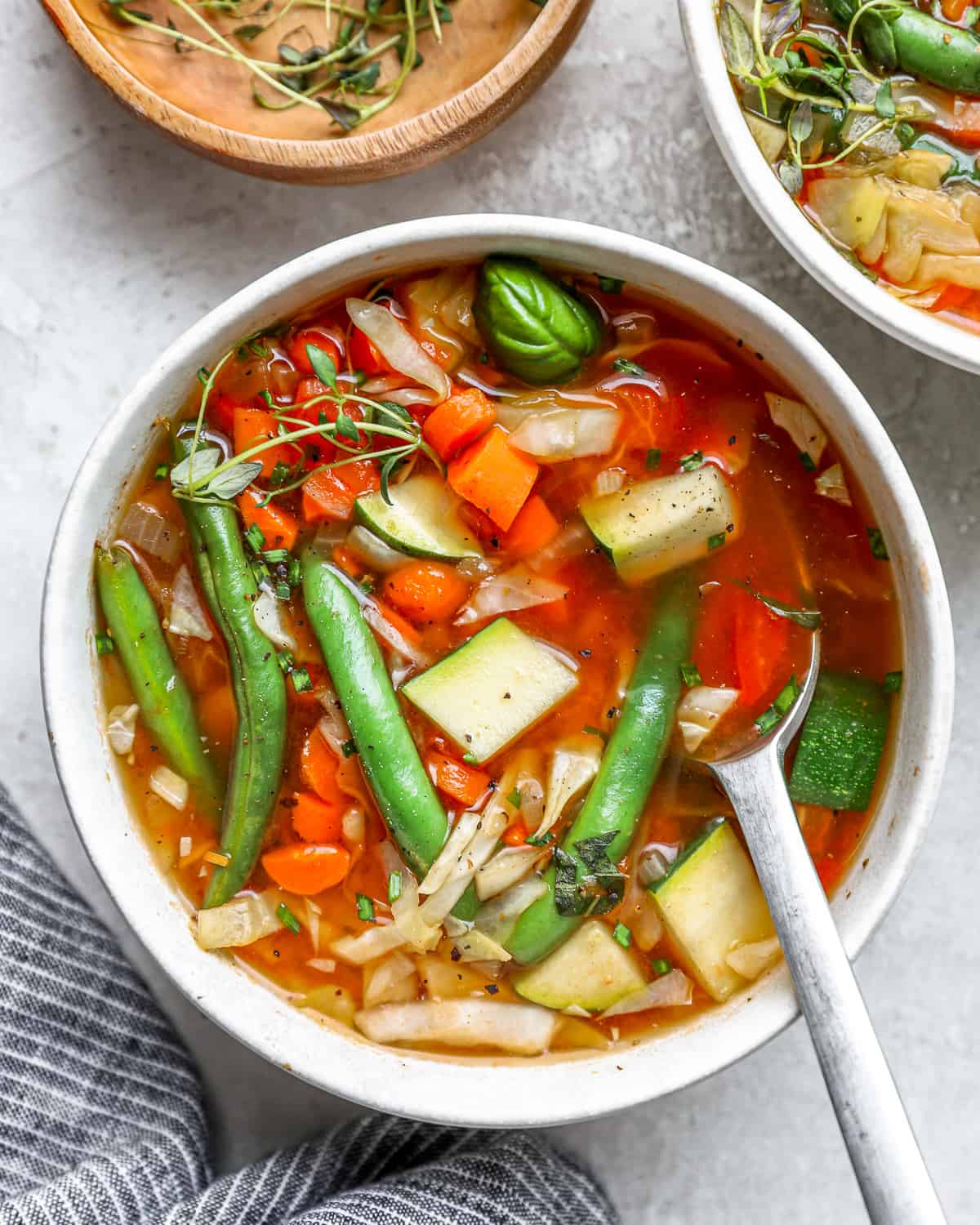 overhead view of a serving of cabbage soup in a white bowl with a spoon.