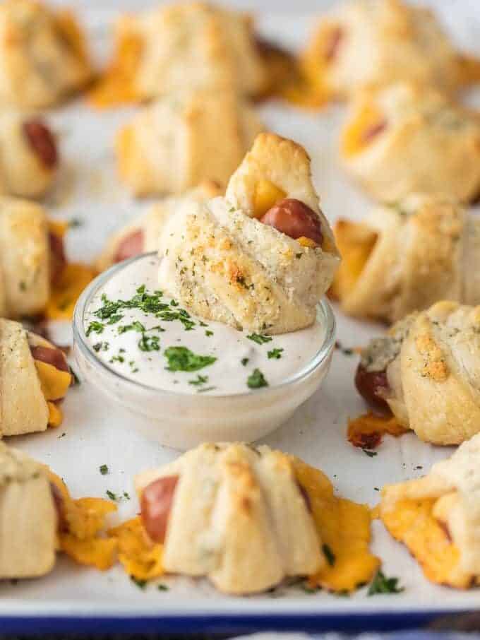 These CHEESY PIGS IN A BLANKET with RANCH PARMESAN BUTTER will be all the rage at your next party. They're easy, fun, and oh so delicious. Lil' Smokies wrapped in sharp cheddar, puff pastry, and brushed with parmesan ranch butter are sure to be a hit.