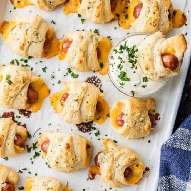 Pigs in a blanket with cheese on a baking sheet.