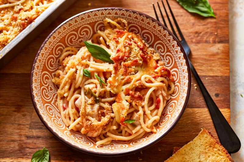 a bowl of pasta and bread on a wooden table.