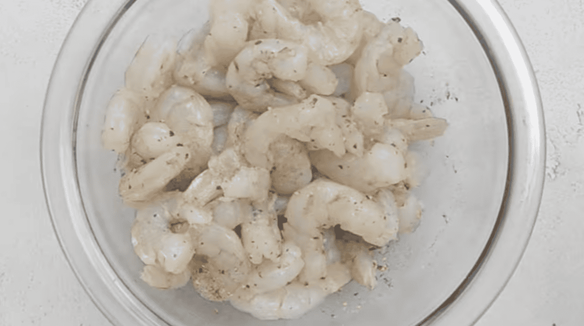 seasoned raw shrimp in a glass bowl.