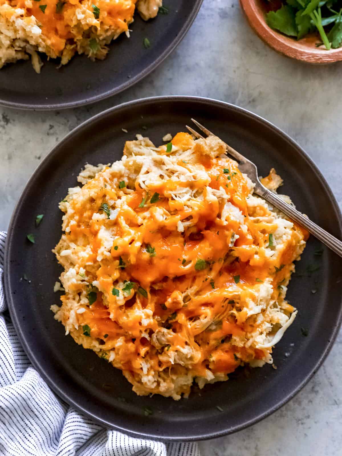 overhead view of crockpot chicken and rice on a black plate with a fork.