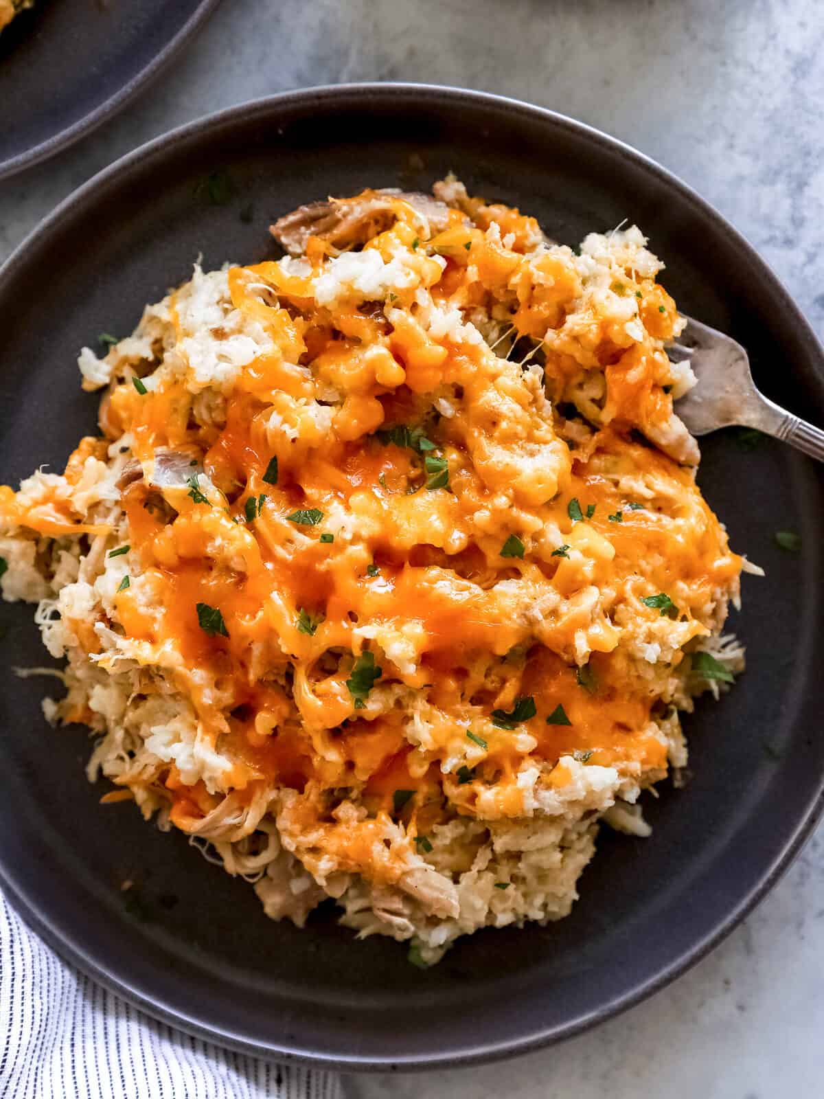 overhead view of crockpot chicken and rice on a black plate with a fork.