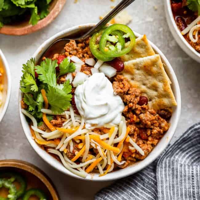 a bowl of chili with sour cream and tortilla chips.