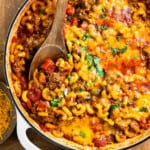 cheesy macaroni and cheese casserole in a pan with a wooden spoon.