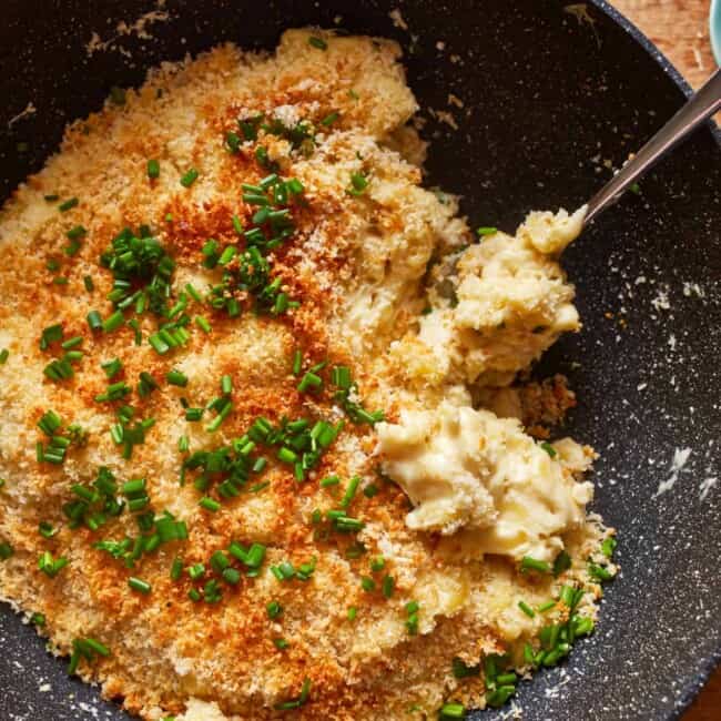 a frying pan filled with cheesy macaroni and cheese.