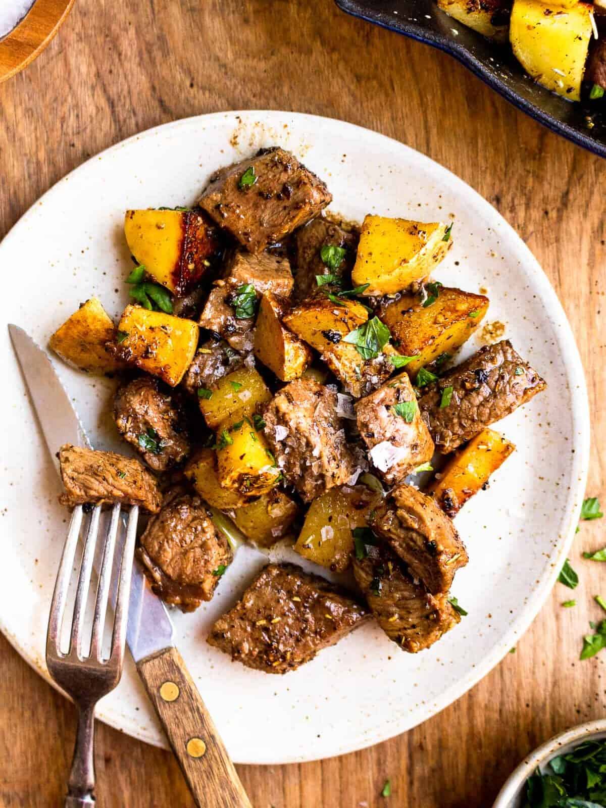 white plate with steak and potato bites