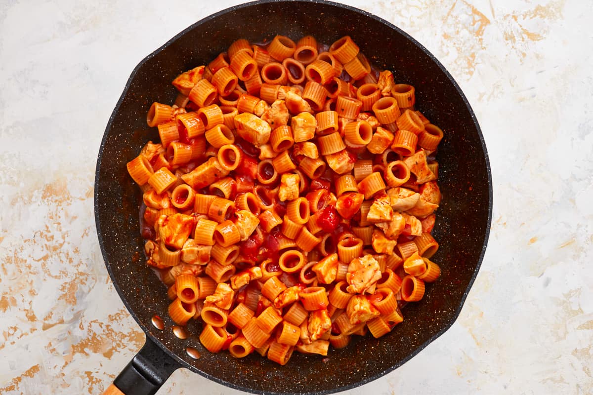 a frying pan filled with pasta and tomato sauce.