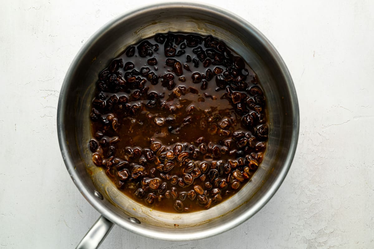 brown beans in a pan on a white surface.