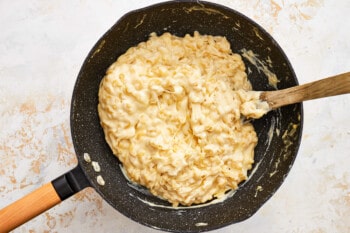 a frying pan full of mashed potatoes with a wooden spoon.