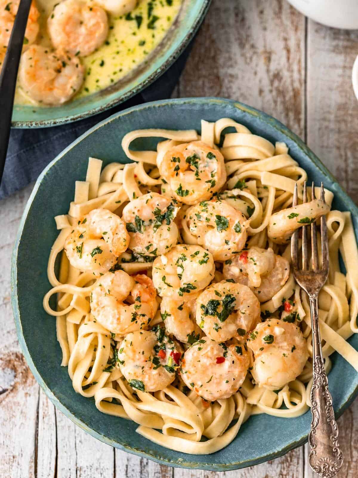 creamy garlic shrimp over pasta in a blue bowl with a fork.