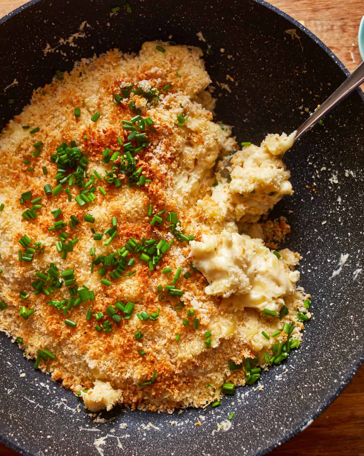 a bowl of mashed potatoes with cheese and parsley.