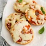 three-quarters view of 4 pizza bagels on an oval serving dish.