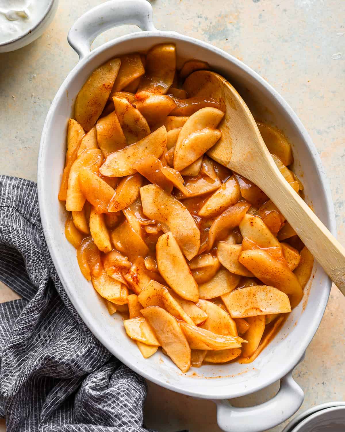 baked apples in a dish with a wooden spoon.