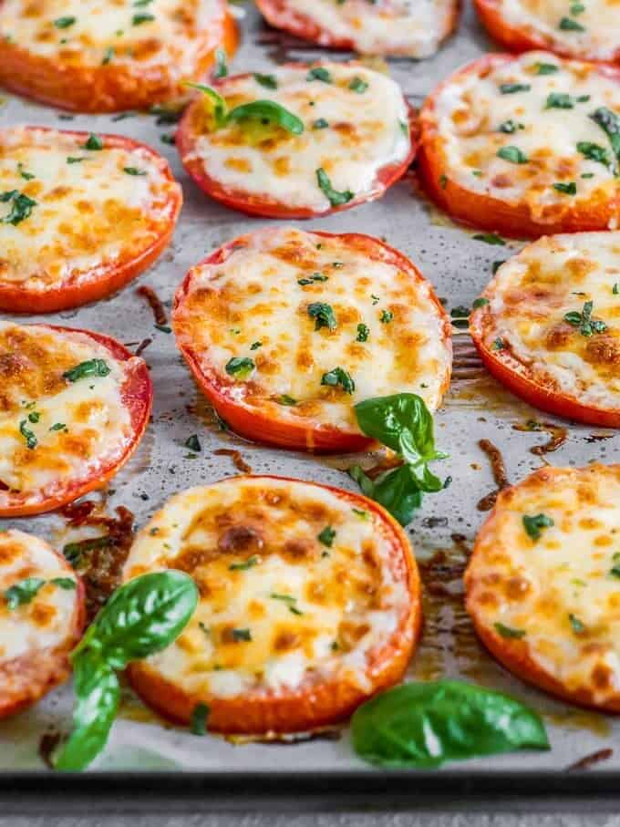 angled shot of baked tomatoes with cheese and basil