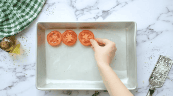 placing tomato slices on a parchment-lined baking sheet.