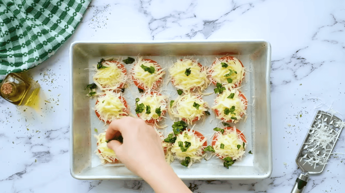 sprinkling basil over cheese-topped tomato slices.