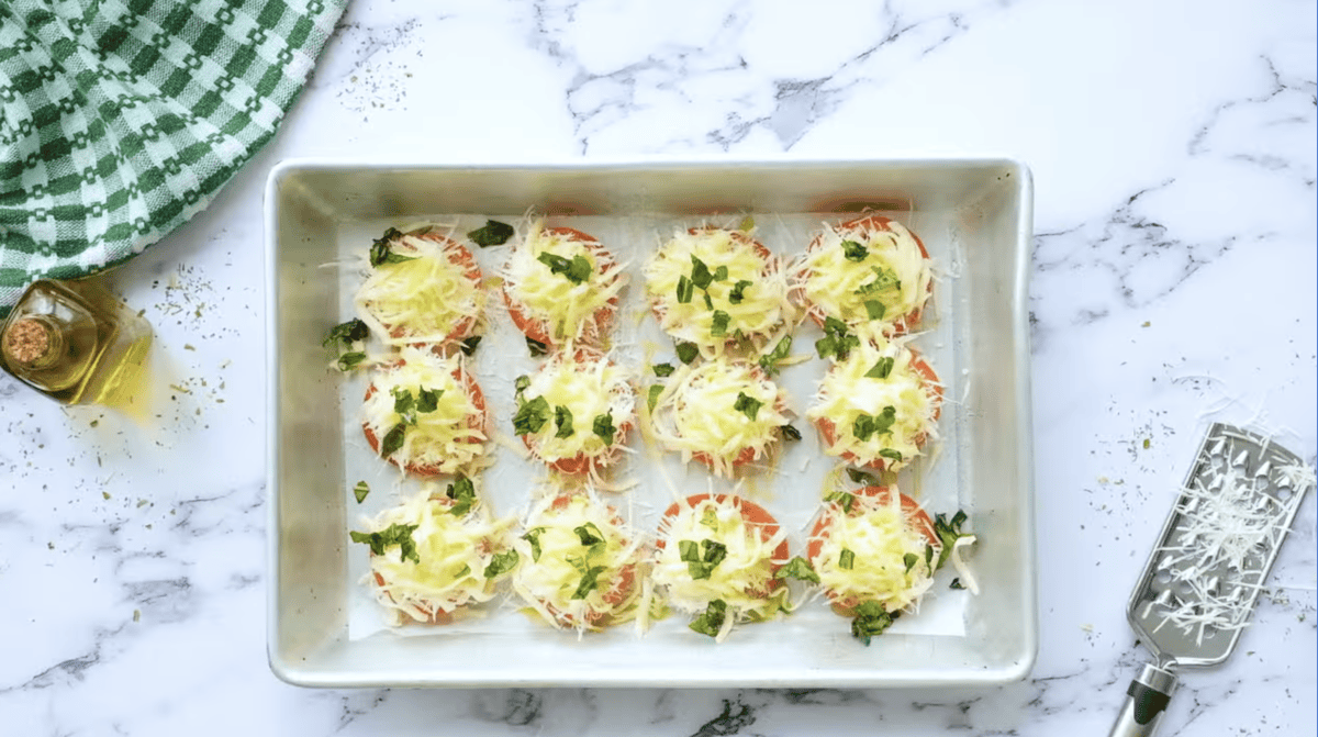 tomato slices topped with shredded cheese and basil.