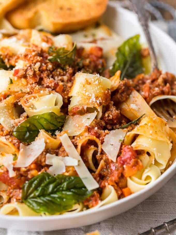 a bowl of pasta with bolognese sauce and bread.