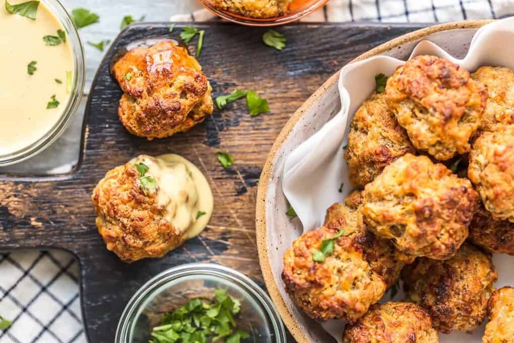 a bowl of sausage balls on a wood board