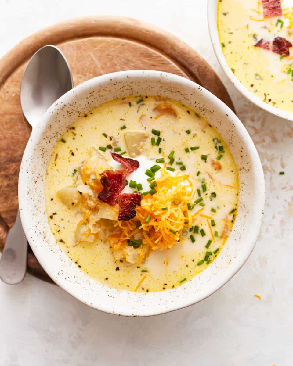 Two bowls of chowder with cheese and bacon.