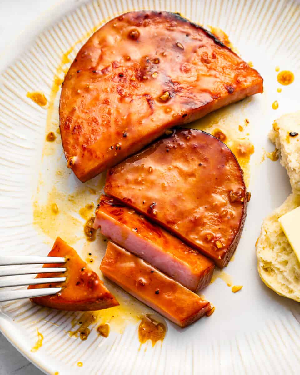 A piece of meat on a plate with a fork.