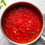 Tomato sauce in a pan with basil leaves.