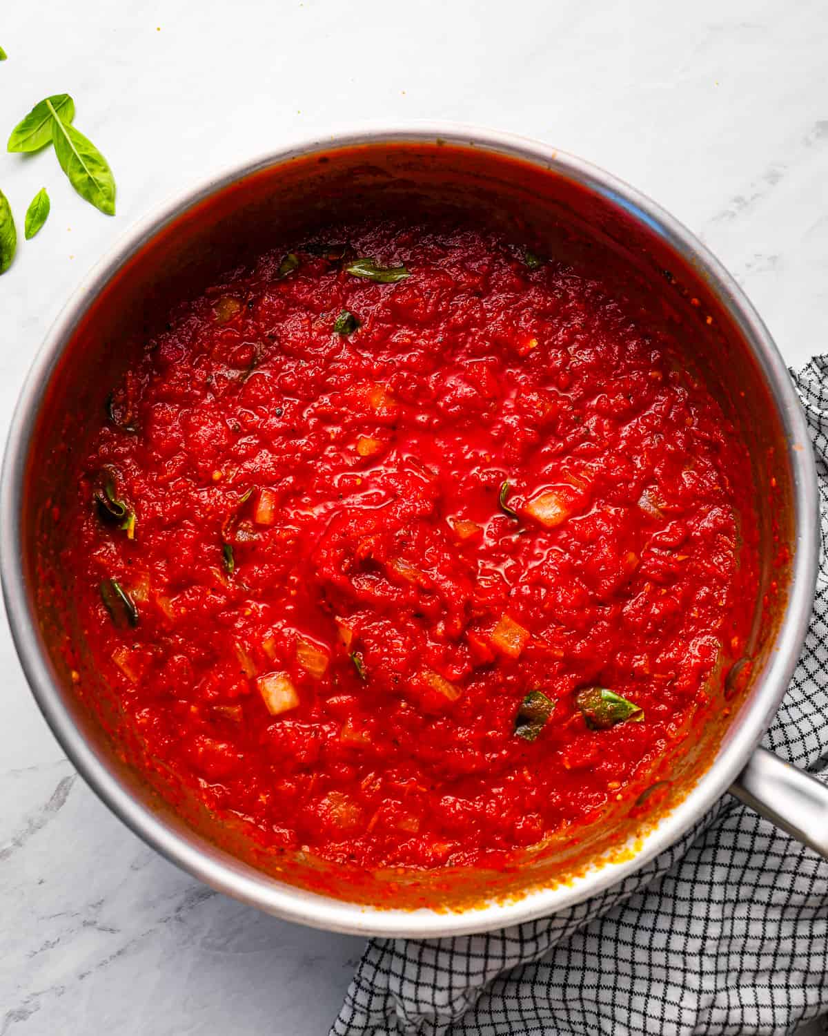 Tomato sauce in a pan with basil leaves.