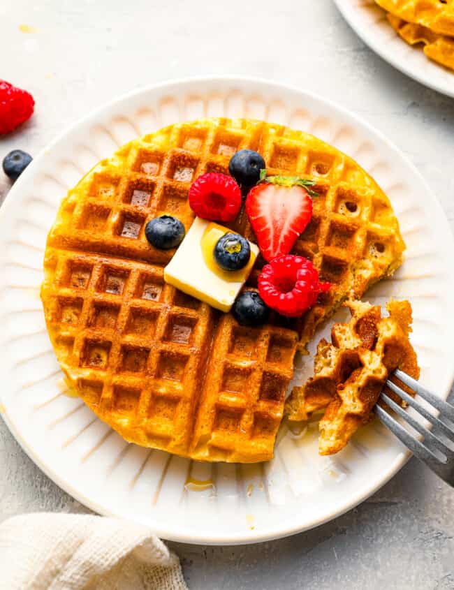 A plate of waffles with berries and a fork.