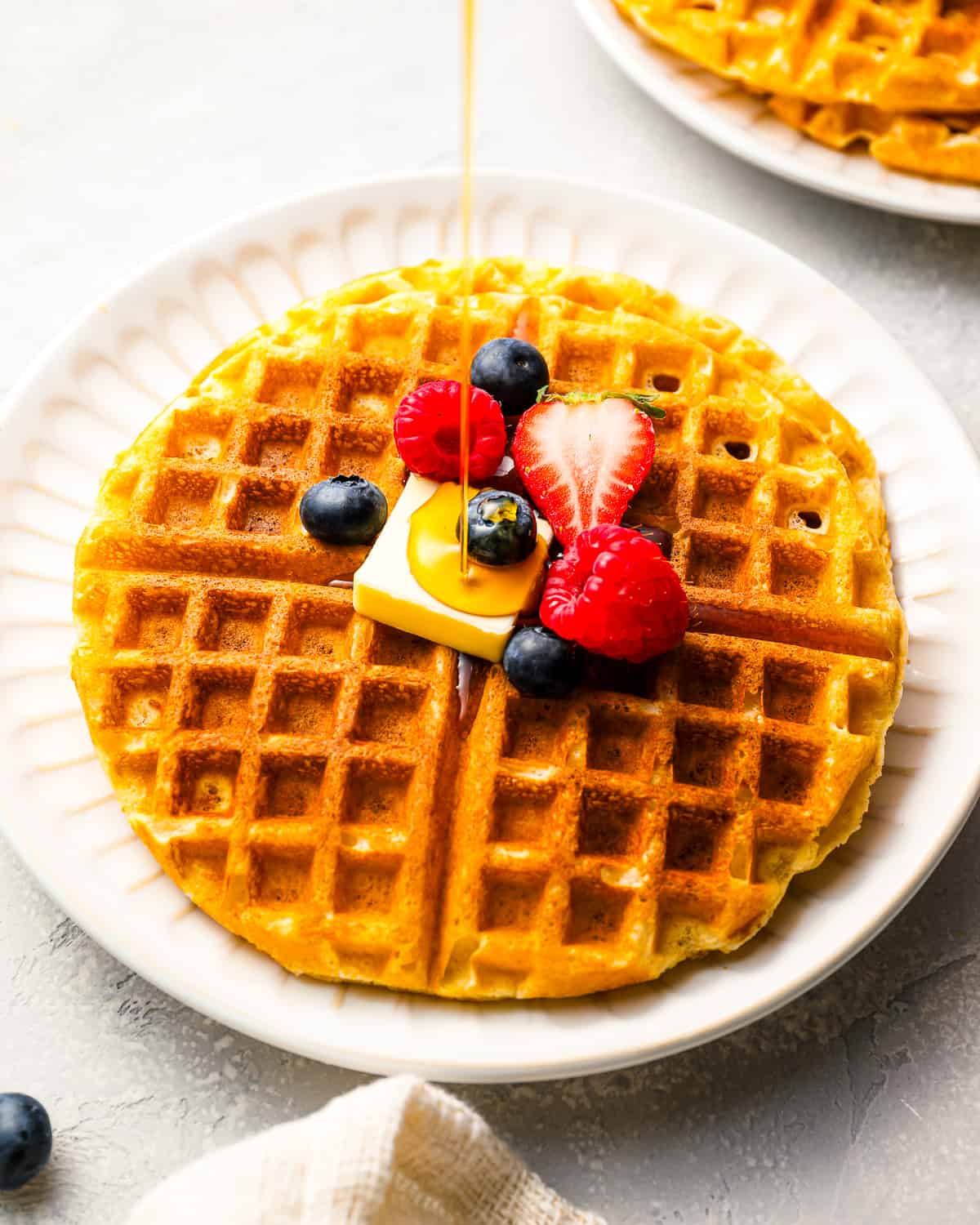 Pouring syrup over a stack of homemade waffles.