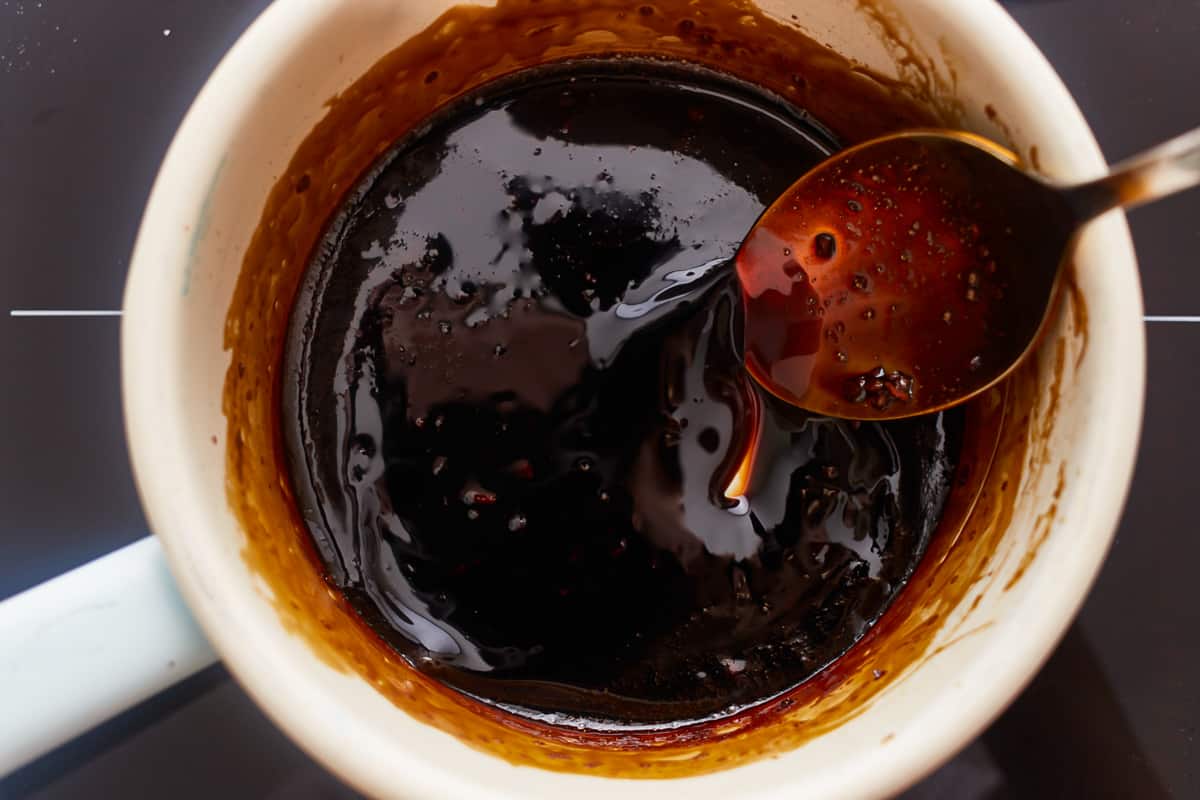 bourbon brown sugar glaze in a ceramic pan with a spoon.