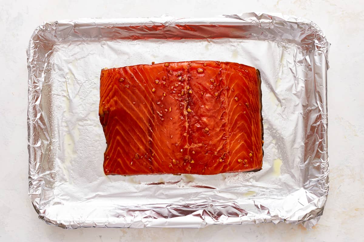 A marinated salmon filet on a baking sheet.