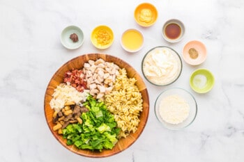 The ingredients for a pasta salad in a wooden bowl.