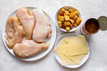 A plate with chicken breasts, cheese, bread and ketchup.