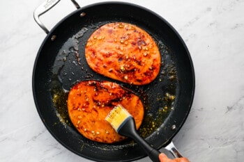 A person is frying two pieces of sweet potato in a pan.