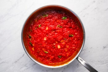 Tomato sauce in a pan on a marble countertop.