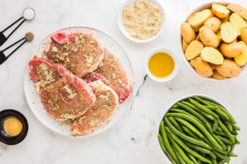 Pork chops and green beans on a white plate.