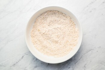 A bowl of flour on a marble table.